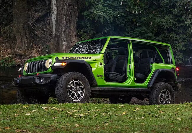 Green 2026 Jeep Wrangler Rubicon parked beside a creek with removable doors installed
