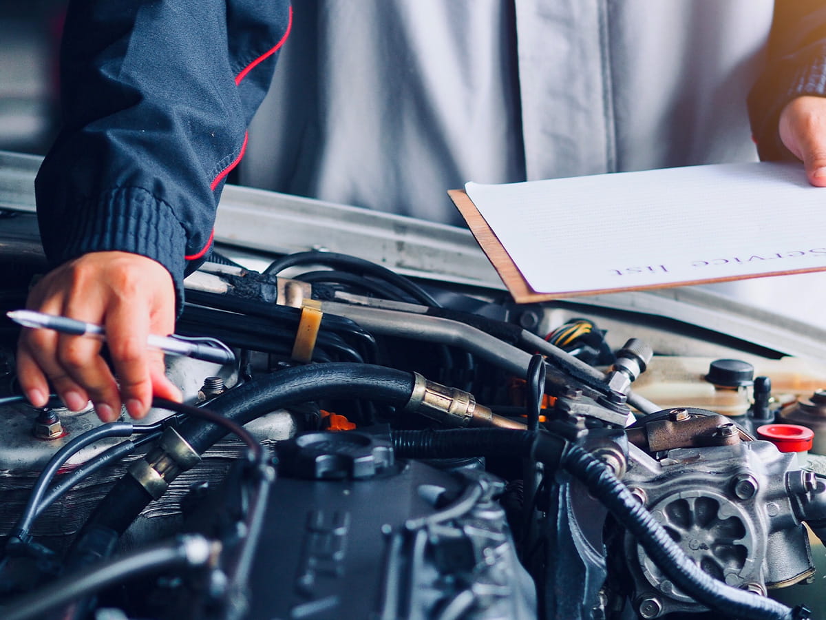 Technician inspecting engine components under an open vehicle hood