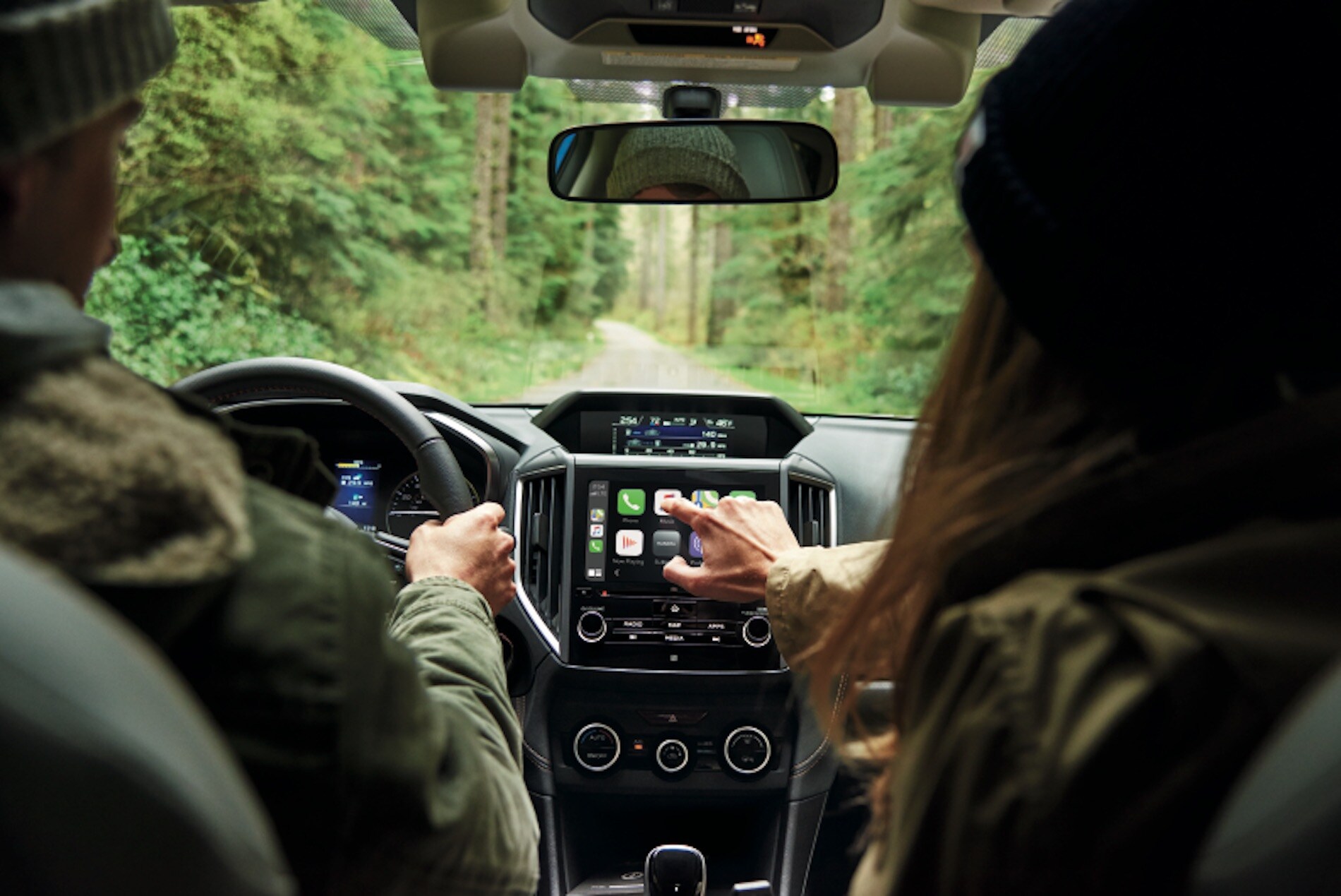 A close up of two people in the front seats of the 2021 Subaru Crosstrek. The woman on the right is reaching for the infotainment panel.