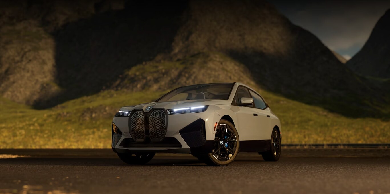 Front and side view of the 2025 BMW iX parked in front of a mountain Front and side view of the 2025 BMW iX parked in front of a mountain