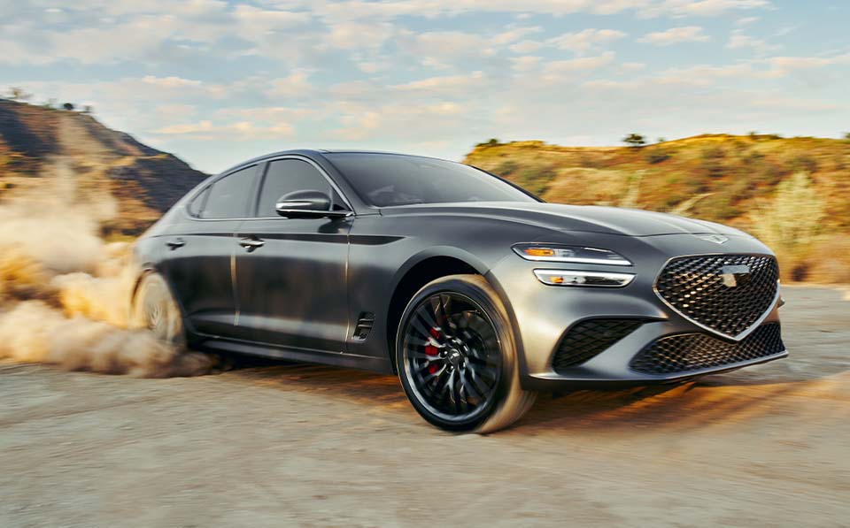 Model Features of the 2022 Genesis G70 at Genesis of York | Dark Silver 2022 Genesis G70 Driving Through Desert and Kicking Up Dirt Behind It