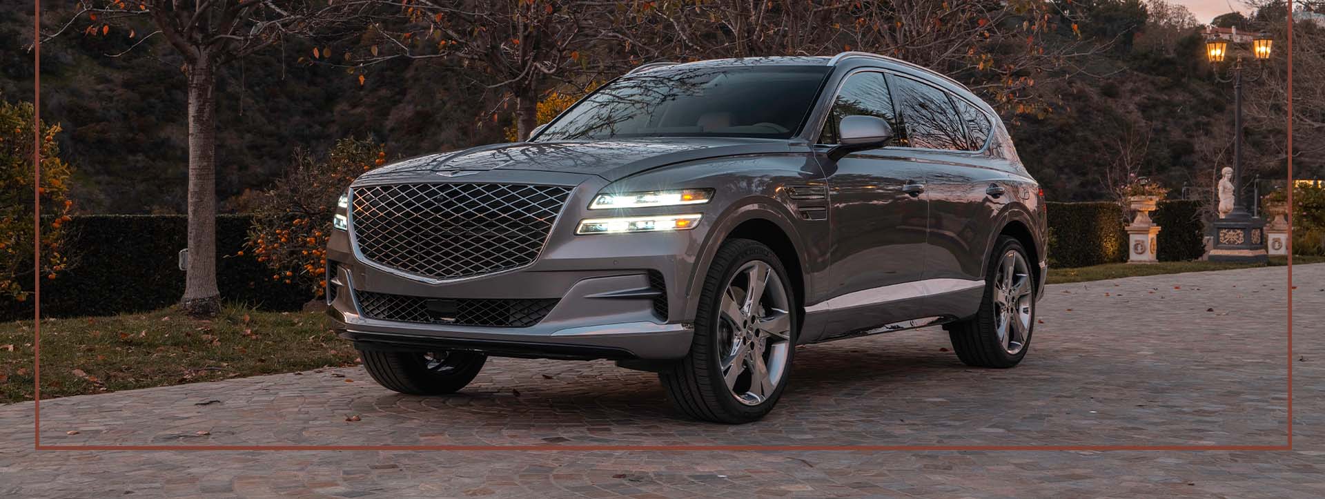 Compare the 2021 Genesis GV80 vs. the 2021 Audi Q7 at Genesis of York | Dark Silver 2021 Genesis GV80 Parked in Driveway at Sunset