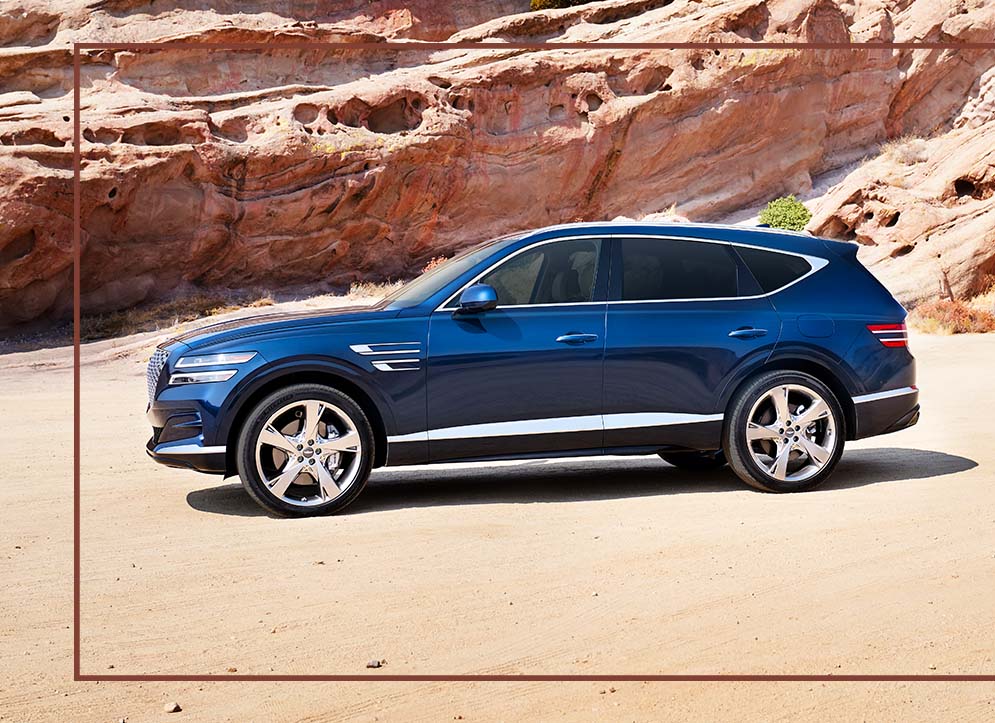 Compare the 2021 Genesis GV80 vs. the 2021 Audi Q7 at Genesis of York | Dark Blue 2021 Genesis Parked in Desert Next to Red Rock Formation