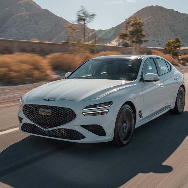 Model Features of the 2022 Genesis G70 at Genesis of York | White 2022 Genesis G70 Driving on Road Through Desert Mountains