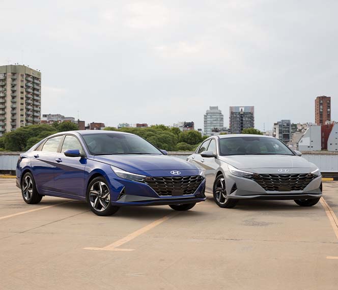Model Features of the 2022 Hyundai Elantra at Jack Giambalvo Hyundai | Blue & Silver 2022 Hyundai Elantra Parked Next to Each Other in Parking Lot with City in the Background