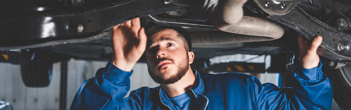 How to Prepare to Trade in Your Car | Jack Giambalvo Hyundai in York, PA | Mechanic inspecting the bottom of a car