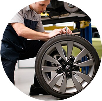 How to check your tires' health at Jack Giambalvo Hyundai | Close-up of Hyundai Technician replacing tire with car on lift in background