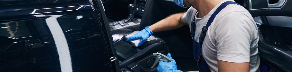 How to Prepare to Trade in Your Car | Jack Giambalvo Hyundai in York, PA | Man wearing bright blue gloves is cleaning the inside of his car