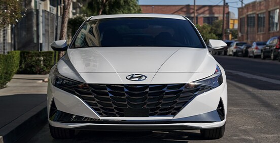 The 2021 Hyundai Elantra vs. The 2021 Hyundai Sonata at Jack Giambalvo Hyundai | Front close-up of Elantra Hybrid in downtown