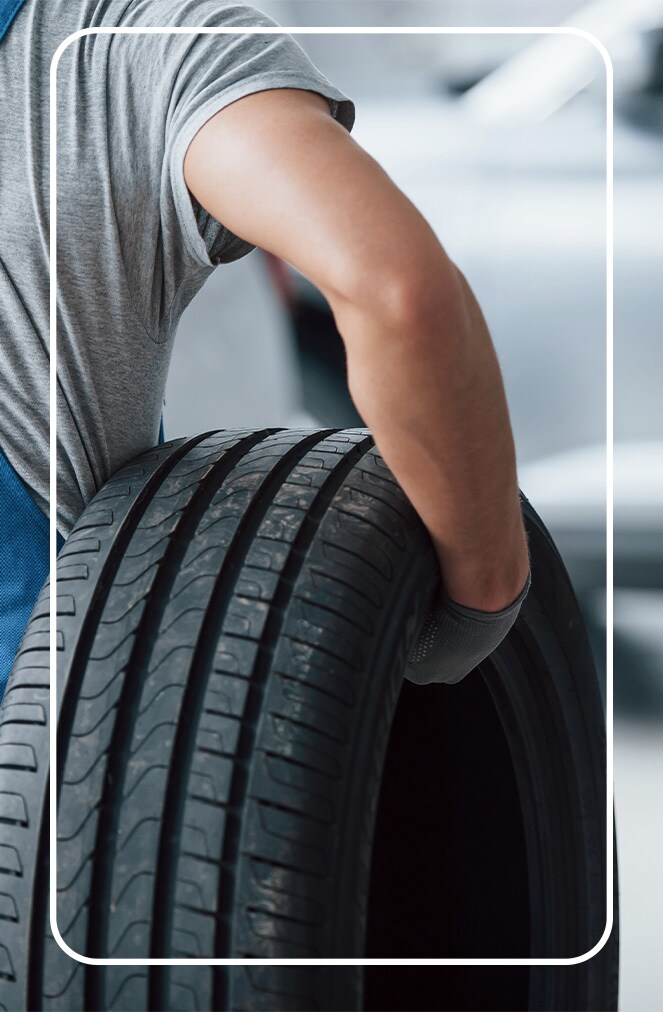 The Cold Facts of Winter Tires | Jack Giambalvo Hyundai in York, PA | Mechanic carrying car tire with one hand