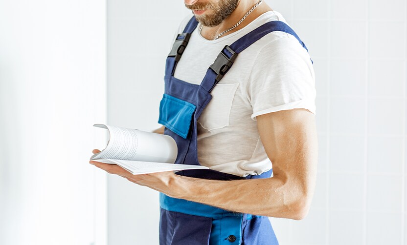 Extend the Life of Your Vehicle at Jack Giambalvo Hyundai in York, PA | Mechanic in blue uniform is reading through owners manual