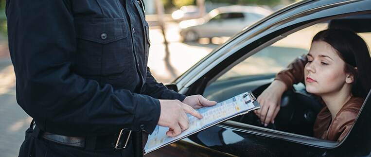 Why You Shouldn’t Drive Around with a Chipped Windshield at Jack Giambalvo Hyundai in York, PA | Police officer holding a clipboard while speaking to a women in her car