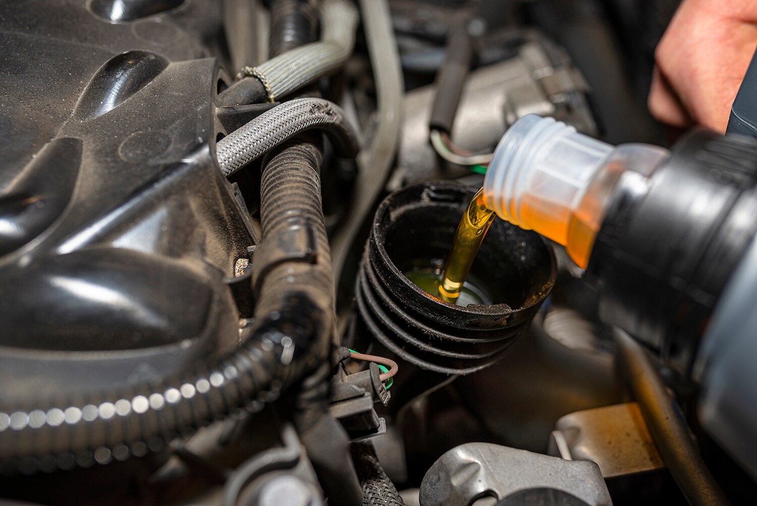 Difference between synthetic oil & conventional oil at Stetler Dodge, Chrysler, Jeep, and Ram | Mechanic filling up engine oil