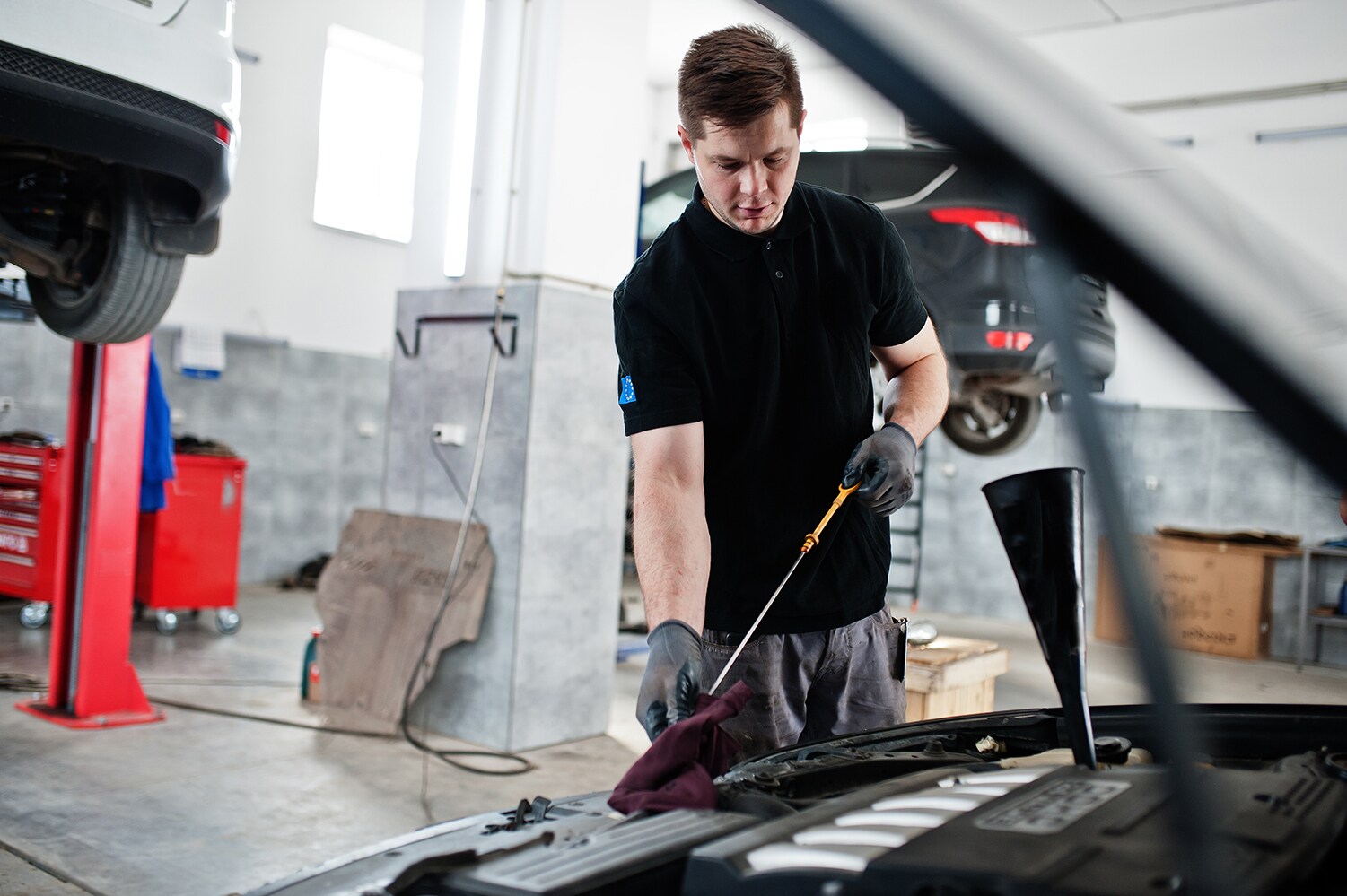 Difference between synthetic oil & conventional oil at Stetler Dodge, Chrysler, Jeep, and Ram | Service technician checking oil in engine