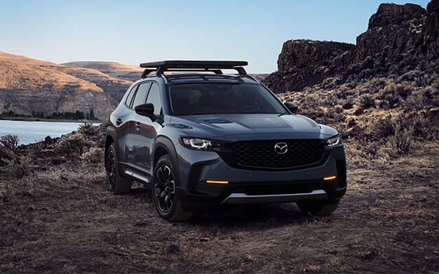 Model Features of the All-New 2023 Mazda CX-50 at Jack Giambalvo Mazda | Black 2023 Mazda CX-50 Parked Facing Right in Front of Water on Rocky and Dirt Road