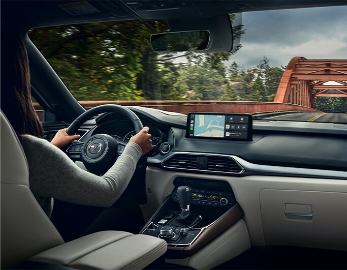 Best MPG At Jack Giambalvo Mazda in York, PA | Interior of a 2023 Mazda CX-9 while a woman is driving with both hands on the steering wheel