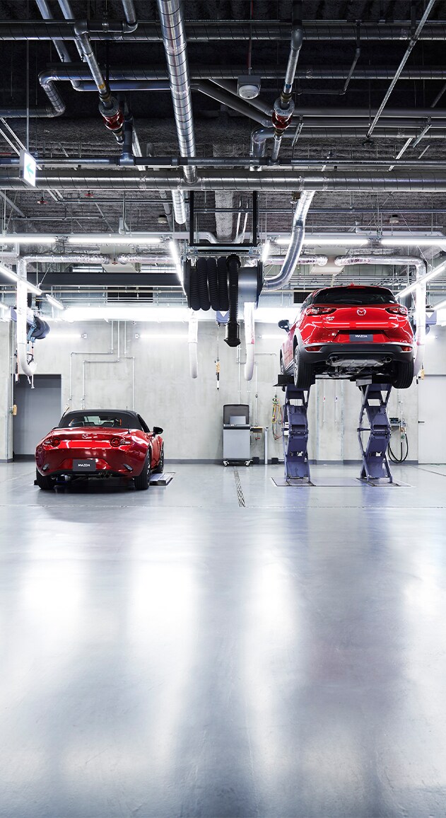 Vehicle Warranty Information at Jack Giambalvo Mazda in York, PA | Two red Mazda vehicles in the service garage of dealership