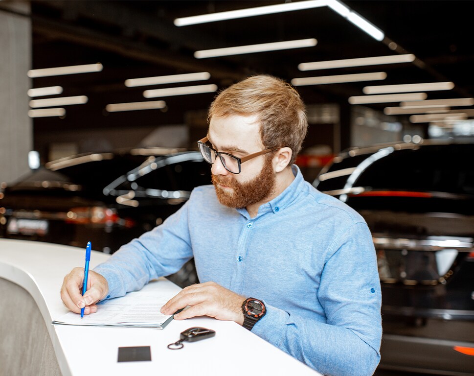 Top Ten FAQs For New Car Buyers in York, PA | Man in blue button up shirt signing new car paperwork