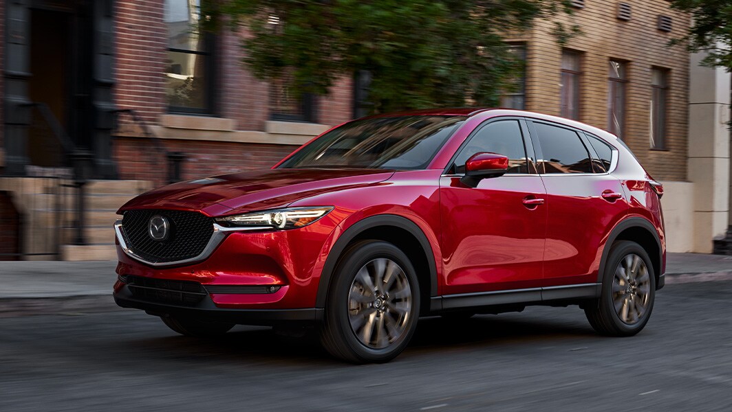 The 2022 Mazda CX-5 vs. The 2022 Mazda CX-30 at Jack Giambalvo Mazda | Red 2022 Mazda CX-5 Driving Through City Streets