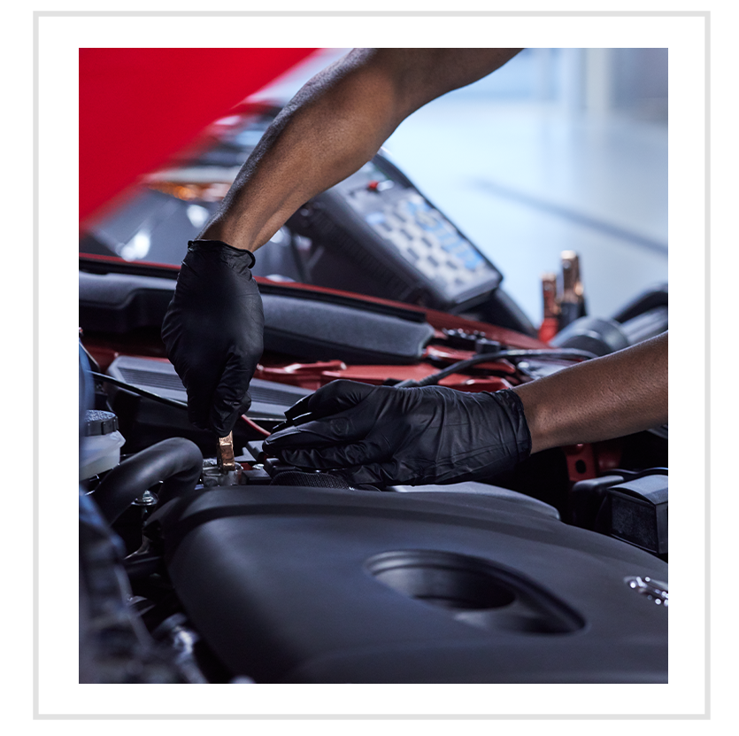 Everything You Need to Know about Your Car Battery at Jack Giambalvo Mazda | Mechanic with black gloves is testing out the battery voltage with special tool