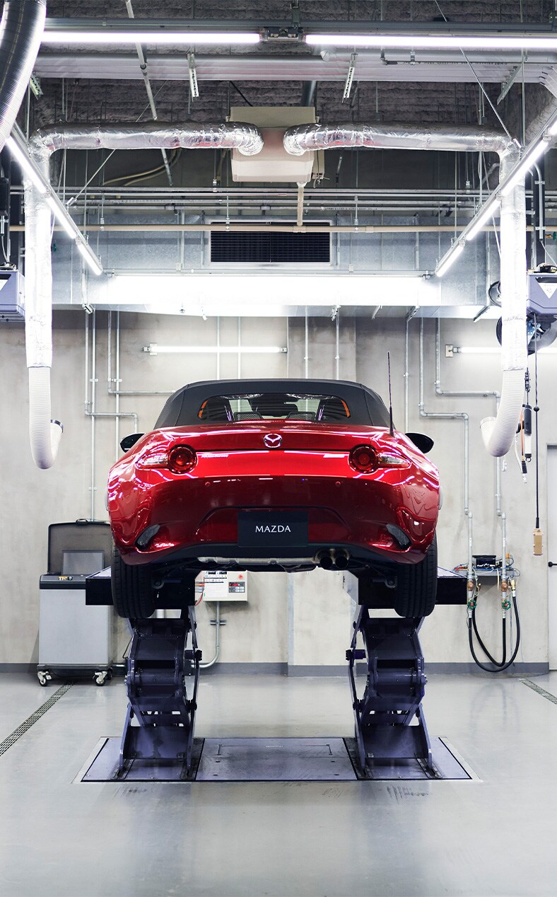 Basic Car Maintenance and Servicing Checklist | Jack Giambalvo Mazda | Red 2023 Mazda MX-5 on car lift inside of a service garage