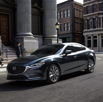 The 2021 Mazda3 vs. The 2021 Mazda6 at Jack Giambalvo Mazda | Mazda6 parked in city infront of library
