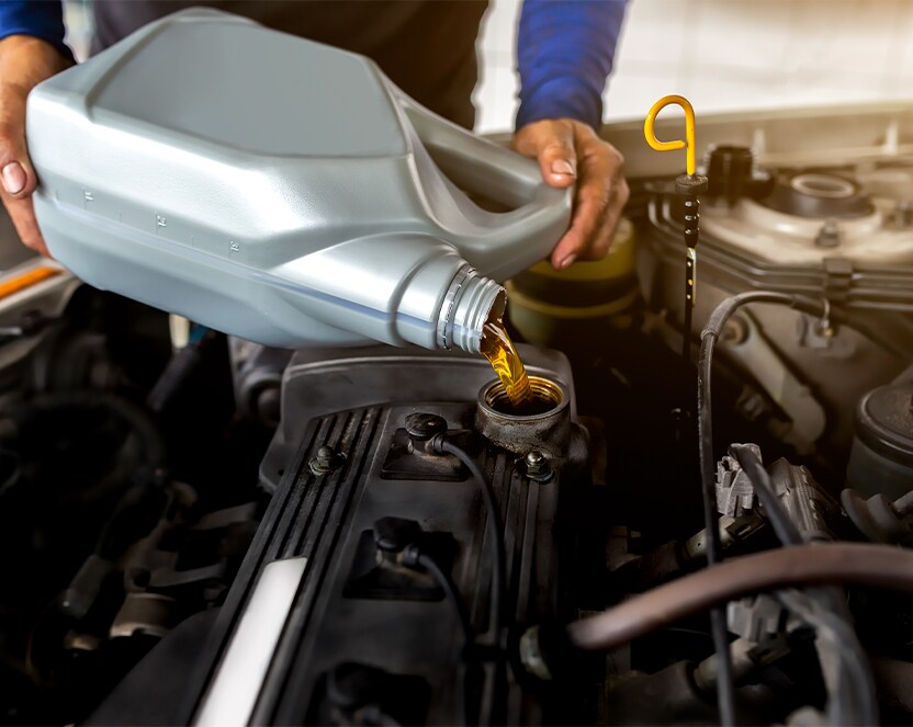Extend the Life of Your Vehicle at Jack Giambalvo Mazda in York, PA | Mechanic pouring new engine oil into the engine he is working on
