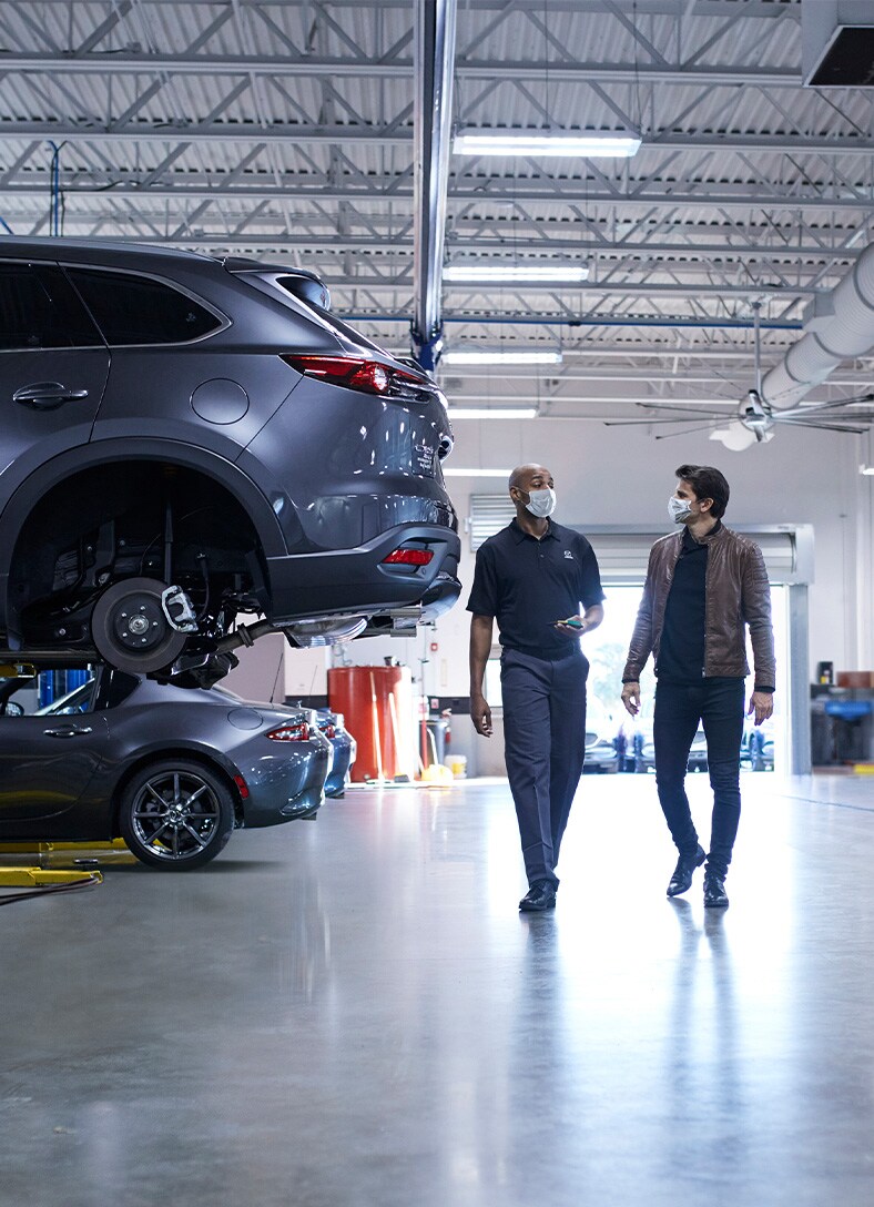 Basic Car Maintenance and Servicing Checklist | Jack Giambalvo Mazda | Service representative showing customer around the mechanic shop