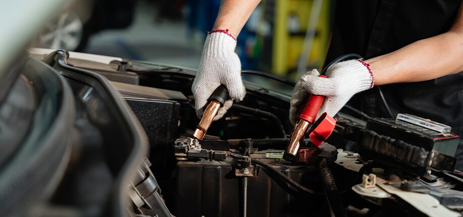 How to Get Your Car Summer Ready at Jack Giambalvo Mazda in York, PA | Man with white gloves using battery cables to test out the battery life for the car