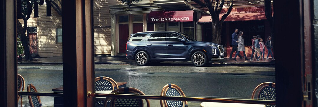 Compare the 2021 Hyundai Palisade vs. the 2021 Toyota Highlander at Jack Giambalvo Hyundai | Palisade parked outside cafe at night