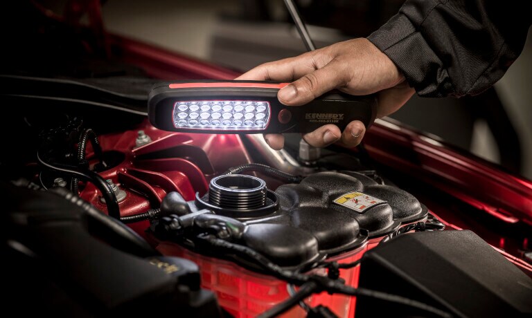 Jaguar technician checking fluid levels with a light