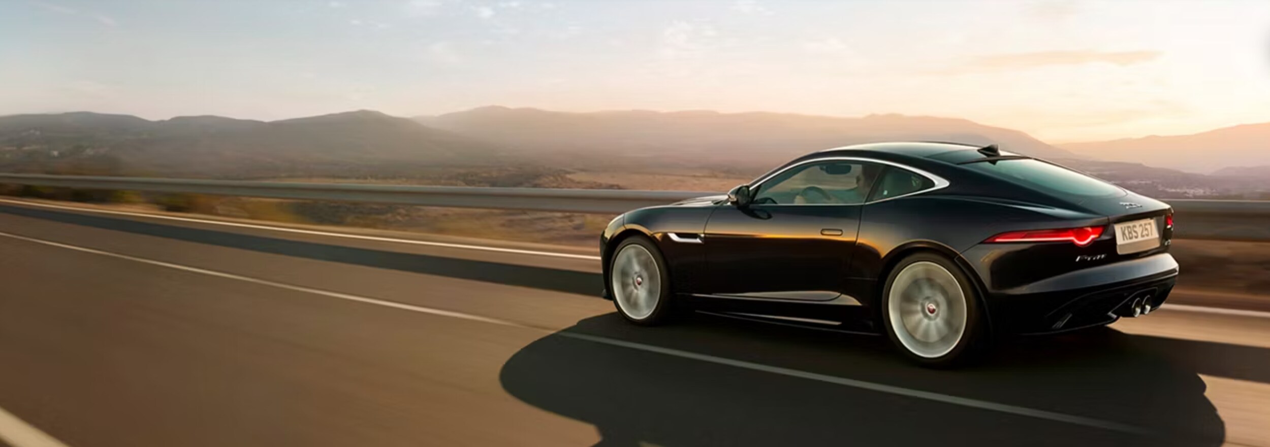 New vs. Certified Pre-Owned Jaguar Side view of a Jaguar vehicle on a bridge with mountains in the background