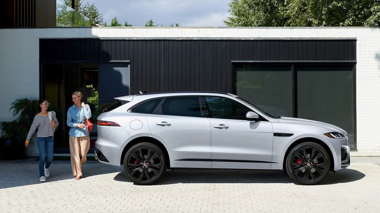 Why finance your Jaguar in Glen Cove Side profile of a parked Jaguar F-PACE with two people walking behind it