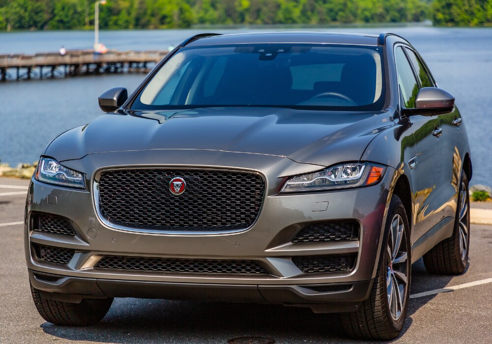 certified-pre-owned-jaguar-for-sale.png A silver Jaguar SUV parked in front of a lake