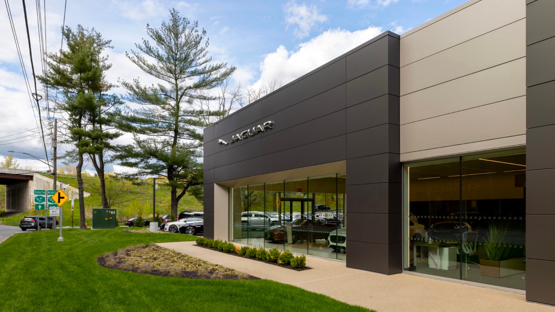 Jaguar Mt Kisco Hours and Directions Exterior view of Jaguar Mt Kisco. Sky is blue and partly cloudy, and vehicles can be seen through the glass windows.