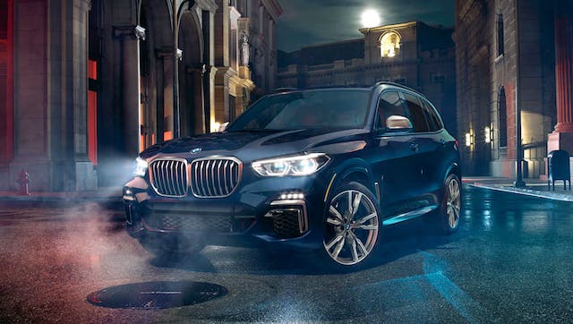 A black 2020 BMW X5 is parked on a city street at night.