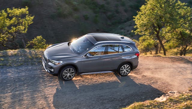 A gray 2020 BMW X1 Sport Activity is driving on a dirt road at dusk. Check one out at your local BMW dealership in Cincinnati, OH.