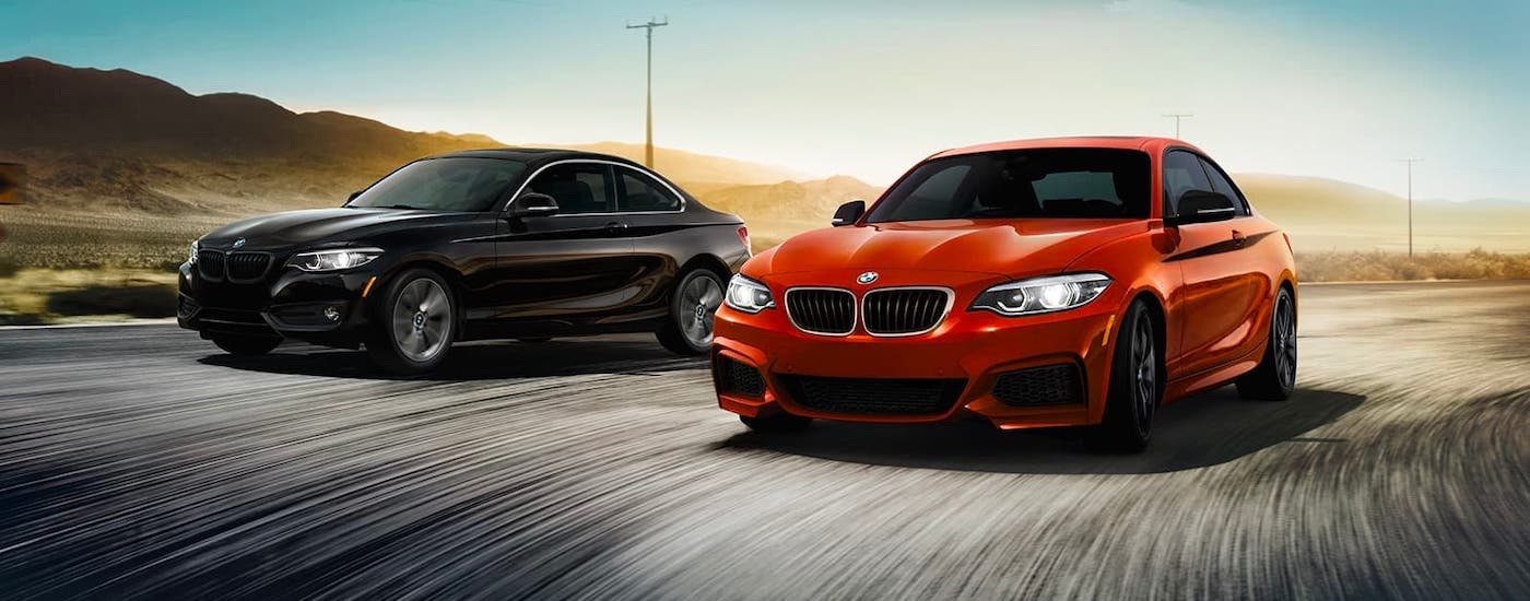 Cincinnati BMW Lease 2021 BMW 2 Series.jpg A black and a red 2021 BMW 2 Series are driving on a winding road.