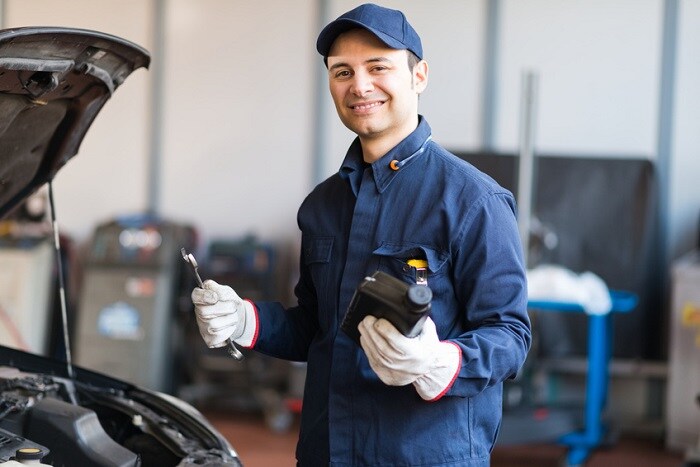Mechanic_Holding_Car_Parts_By_Car.jpg