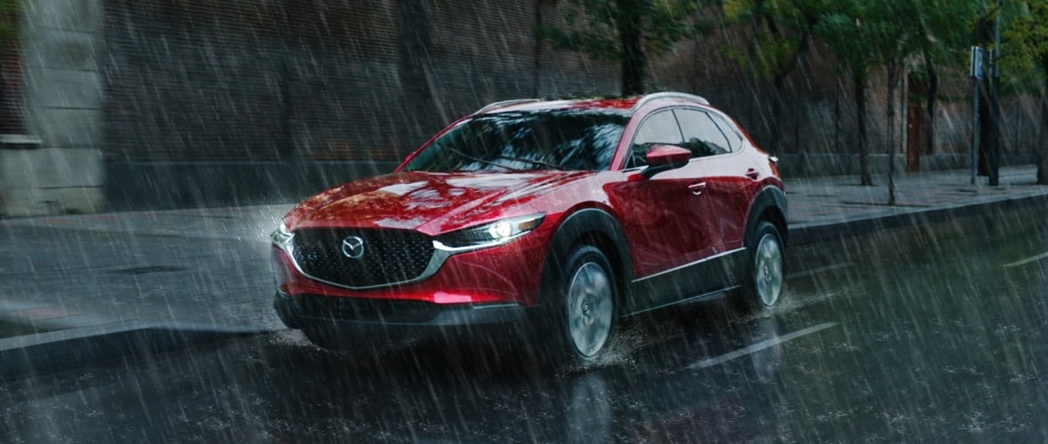 Red Mazda CX-30 driving in rain. Sold at Jake Sweeney Mazda Tri-County, Cincinnati's top dealer.