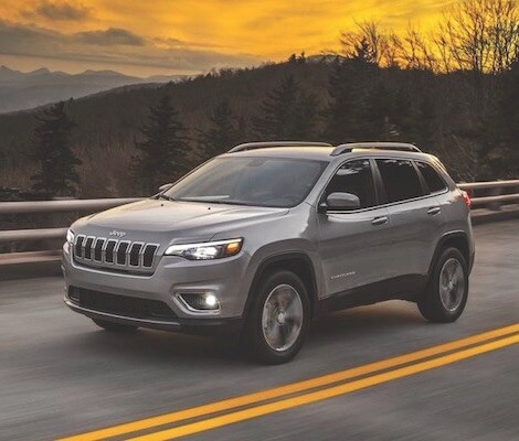 2019 Jeep Cherokee A silver 2019 Jeep Cherokee driving down a road at sunset