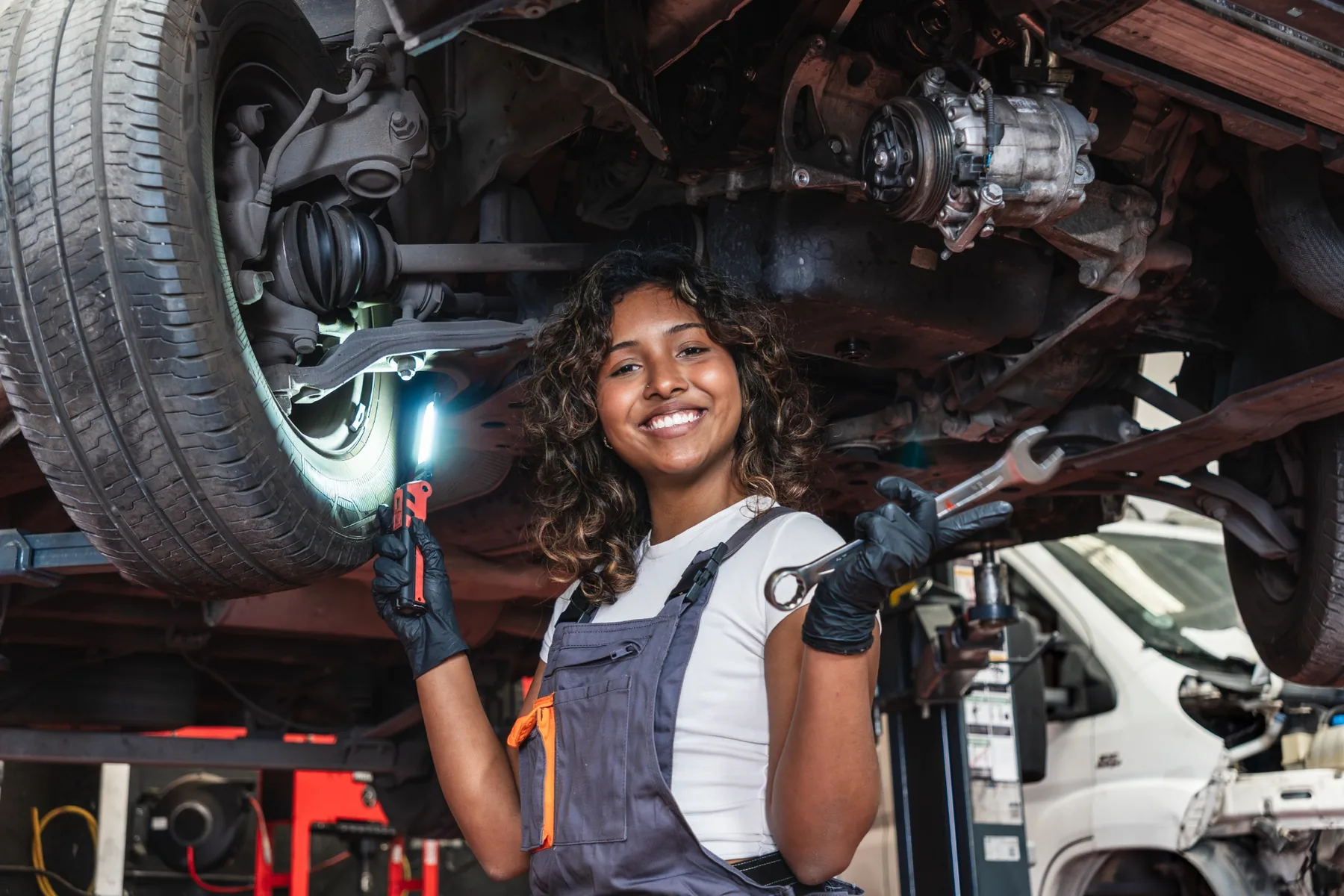 Jeep Recall Service Inspection in Las Vegas Smiling Jeep service technician holding an inspection light beneath a lifted vehicle