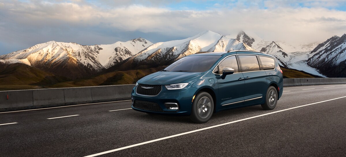 2021-Chrysler-PacificaHybrid-Pinnacle-Van-L02 (2).png blue Chrysler Pacifica minivan driving down a highway
