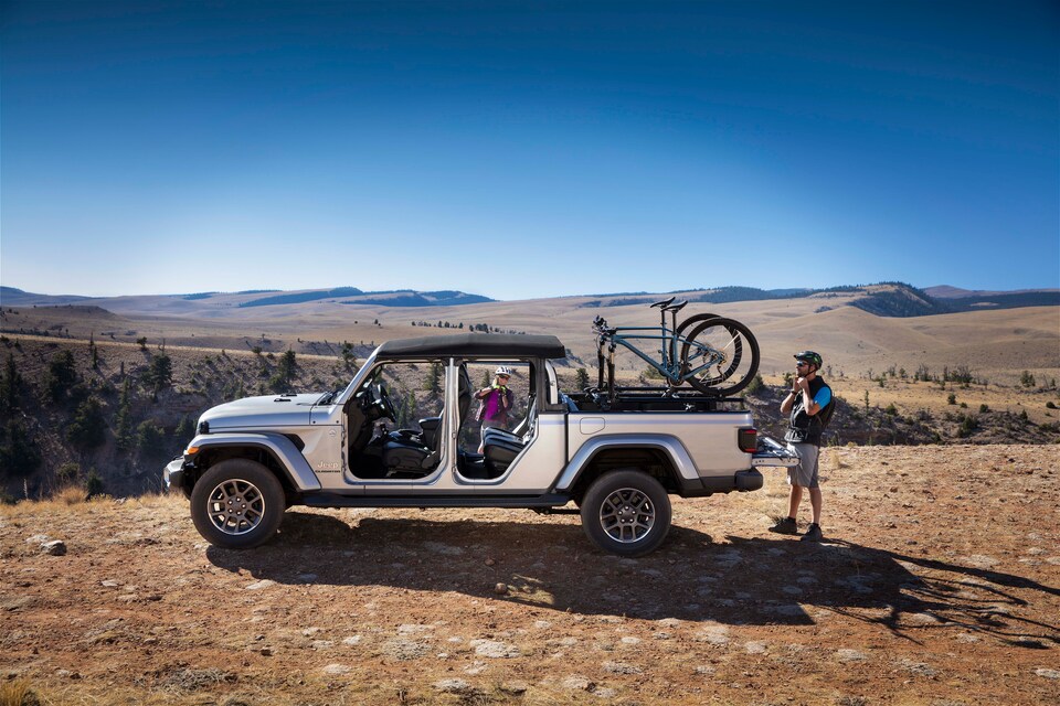 2022-Jeep-Gladiator-Overland-Truck-L04.png silver Jeep Gladiator truck parked with the doors and roof removed, bikes in the truck bed