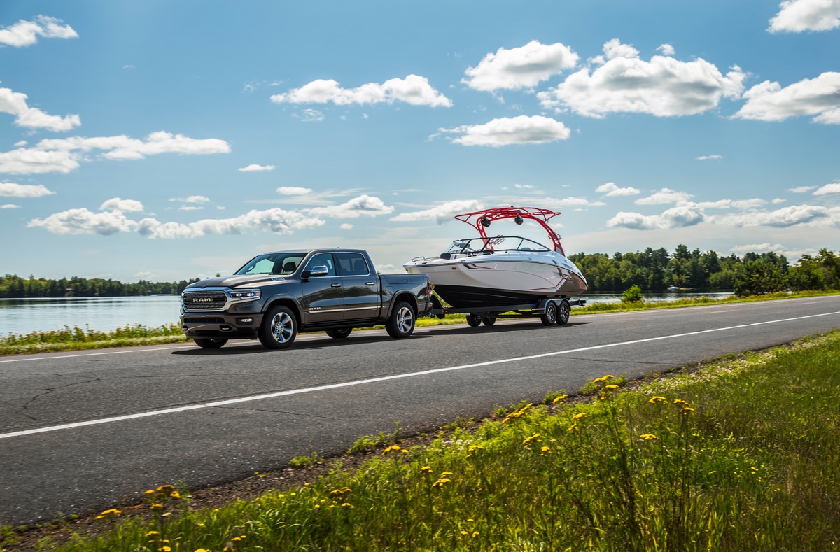 2022 Ram 1500 Limited CrewCab Truck.png dark blue Ram 1500 towing a boat near a lake