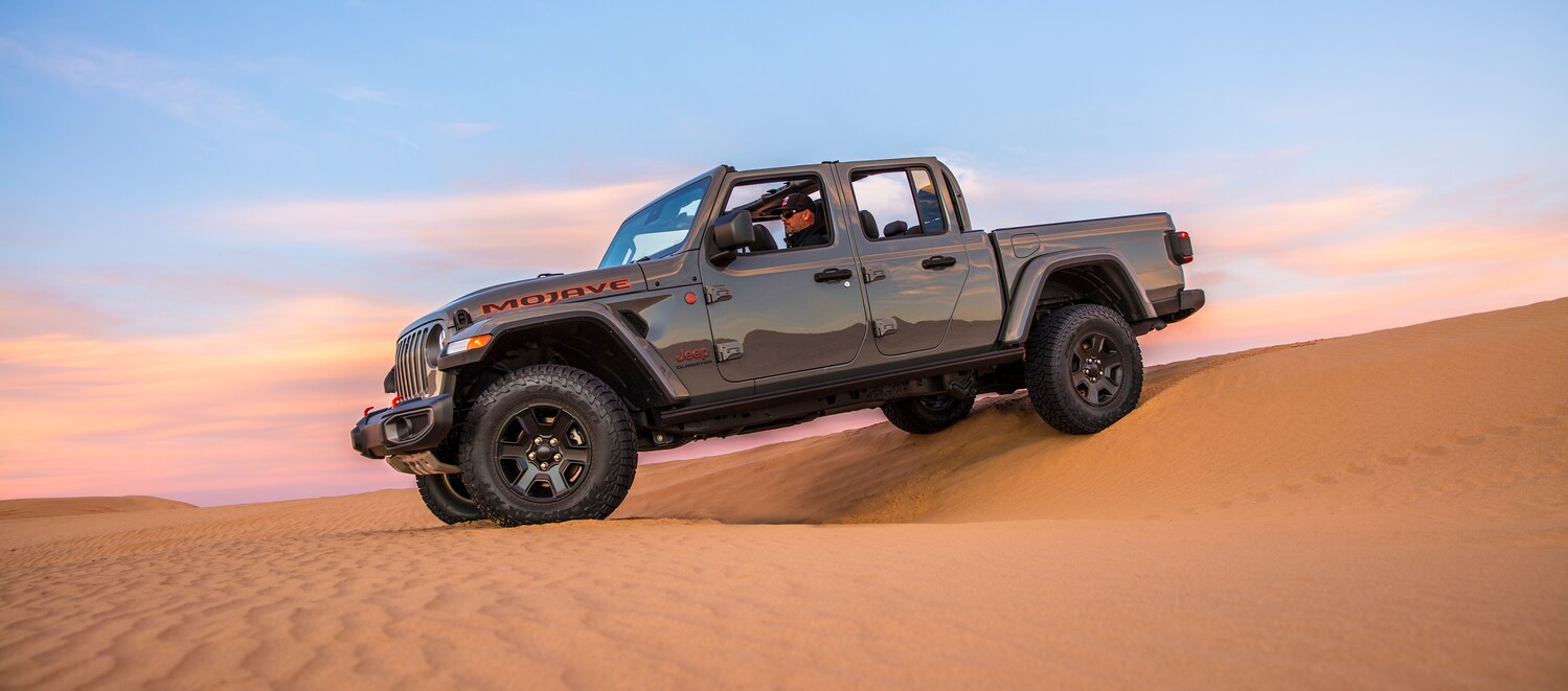 2021-Jeep-Gladiator-Mojave-Truck-L10 (2).png silver Jeep Gladiator truck driving on desert sands