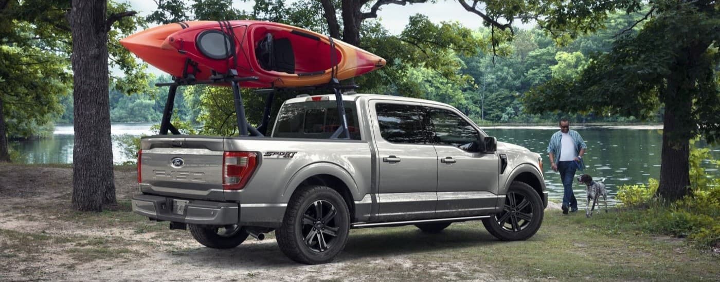 2023 Ford F-150 Sport - Kayak.jpg A silver 2023 Ford F-150 Sport is shown with kayaks on the roof next to a lake.