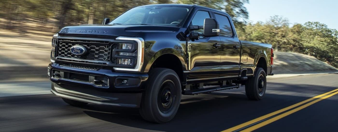 2023 Ford F-250 XL STX - Blur.jpg A black 2023 Ford F-250 XL STX is shown driving on an open road.