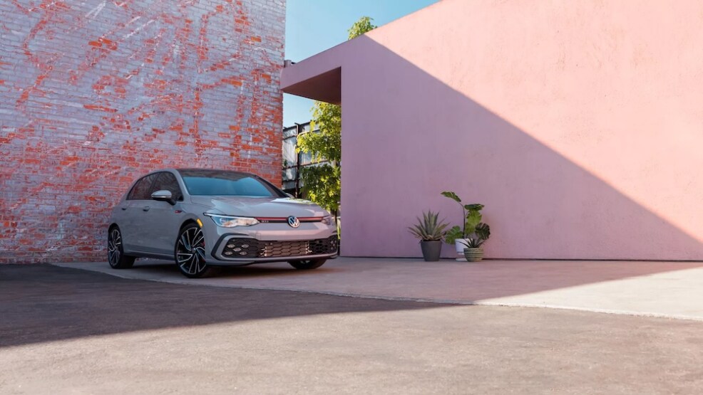 A silver Volkswagen sedan parked beside a pink wall