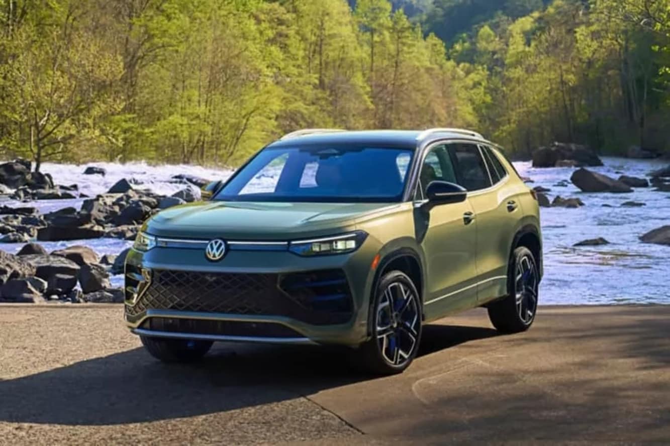 A green Volkswagen Tiguan parked beside a river